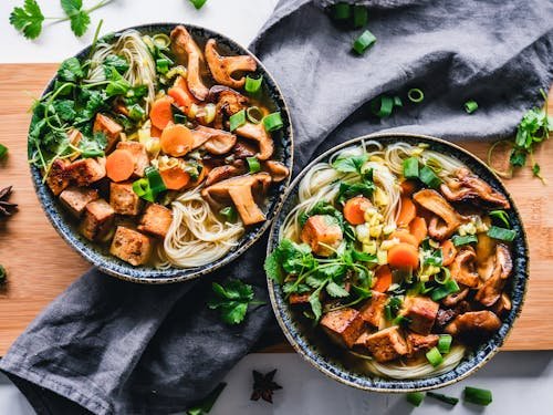 Free A vibrant noodle bowl with tofu, mushrooms, and fresh vegetables, perfect for a healthy meal. Stock Photo