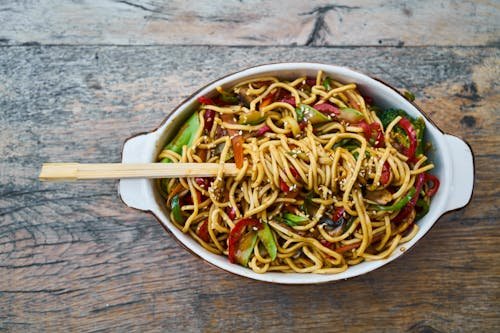 Free Tasty stir-fried noodles with fresh vegetables and sesame seeds, perfect for a healthy meal. Stock Photo