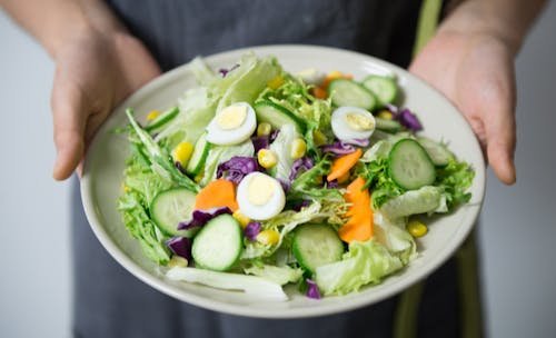 Free Freshly prepared salad with cucumber, lettuce, carrots, and egg slices presented on a plate. Stock Photo